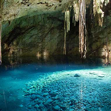 Een turquoise glinsterende plas water in een grot. De kleur wordt veroorzaakt door fijnvermalen mineralen die zweven in het water.